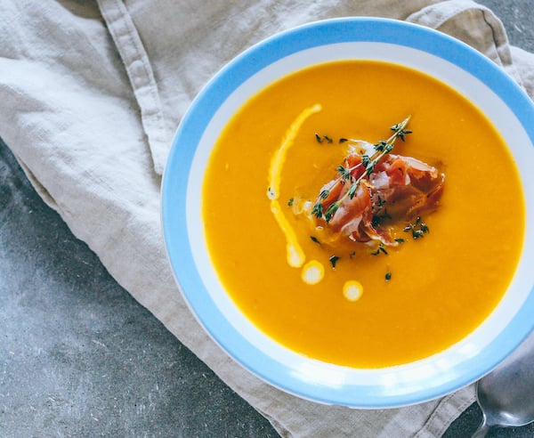 plate-of-pumpkin-soup-with-jamon-garlic-thyme-and-cream-on-gray-background
